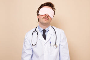 A man in a sleeping mask to illustrate a sleep doctor.