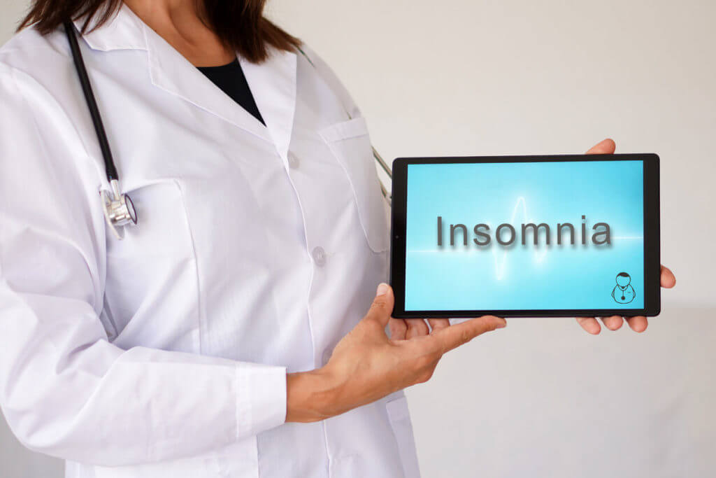 A faceless female sleep doctor with a tablet on which Insomnia is written on.