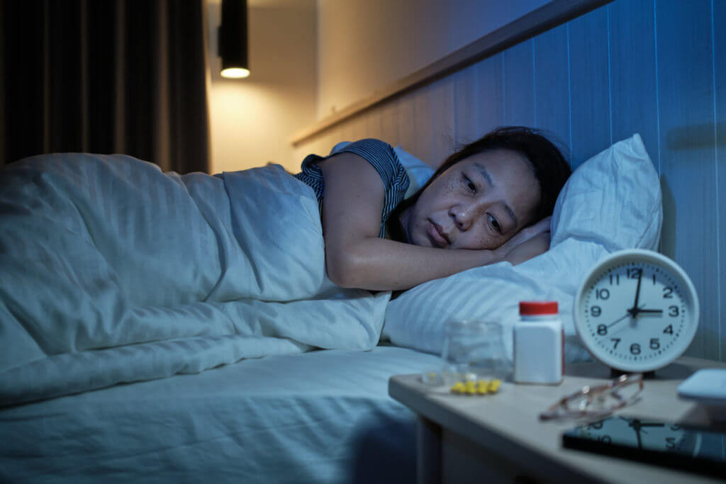 Asian mature woman has a sleep disorder from drug side effects and insomnia.