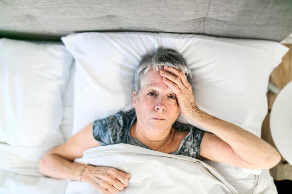 Senior aged woman on bed at home and suffering from insomnia.