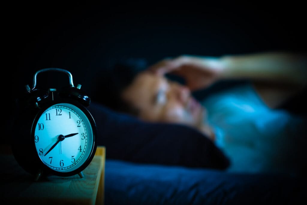 A man in bed suffering insomnia and sleep disorder thinking about his problem at night.